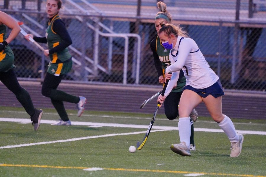 A field hockey teammate hits a ball during a game. This year, the team has had to adjust to multiple changes due to COVID.