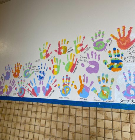 A group of senior handprints has already begun to fill a section of the wall. Each hand has its own unique colors and designs. 
