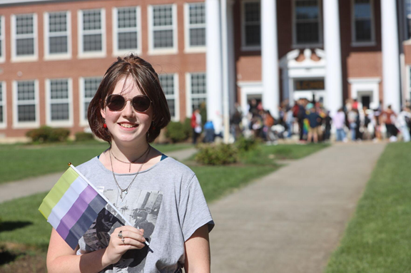 This photo captures Felicity Banner (they/them), organizer of the walkout at Loudoun County High School, standing in front of the students participating in the walk out. Banner is holding a Non-Binary pride flag.