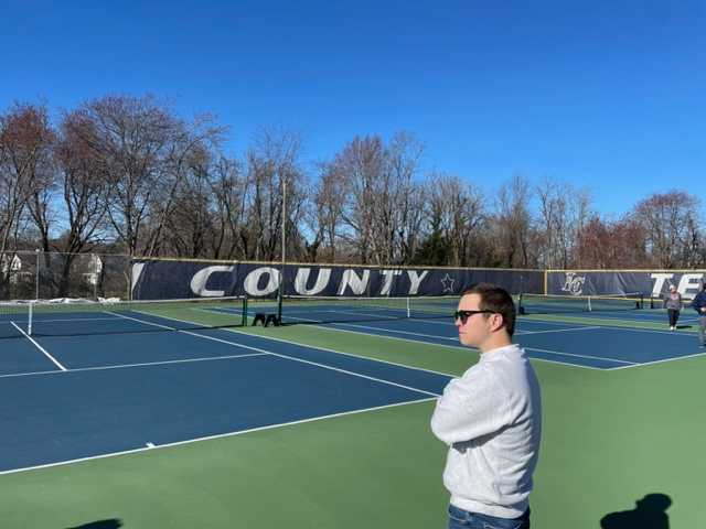 Shuyler Henderson looks on as the players warm up during practice on March 13. This is Hendersons first year as Boys Tennis Coach. Photo by William Kluttz.