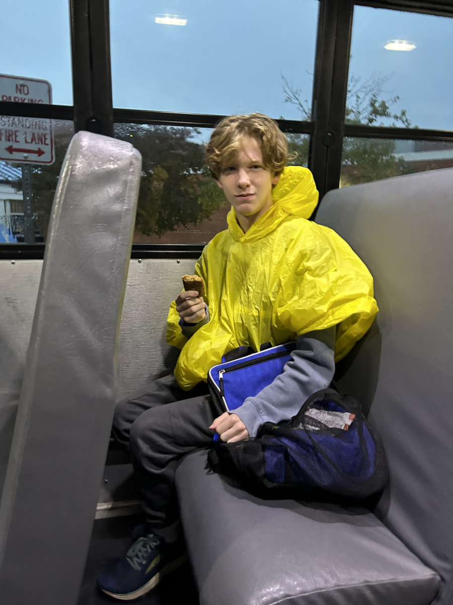 Senior Crawford Holmes sits in the bus with his granola bar and bright, yellow poncho as he gets ready for his race in the rain.