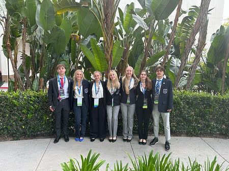 (Left to right) DECA students Will Dunleavy, Abby Graham, Maura Santelli, Alaina Plasmier, Sophie Webb, Maggie Salem, and Jake Andrews pose outside of the Anaheim Convention Center. Students qualified at the local level, and competed at the national level in California.