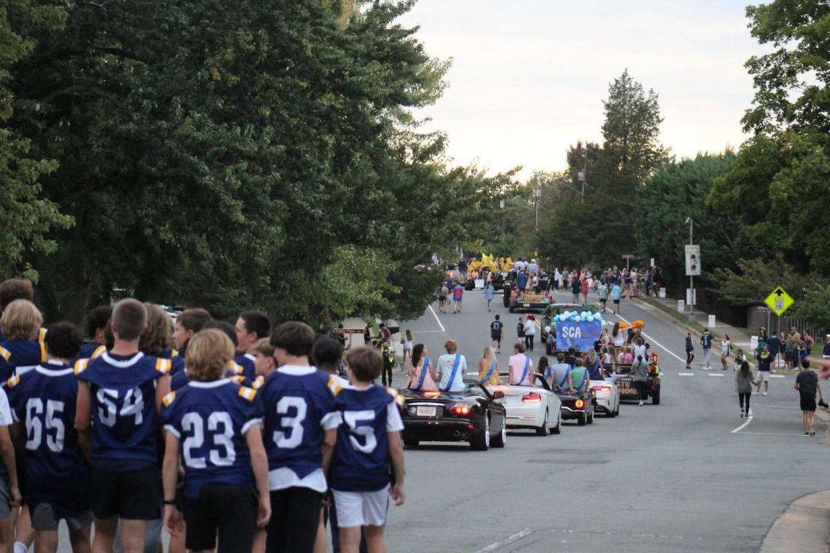 Parade marches down Catoctin circle. At the back is the football team. After them is the Homecoming Royalty and Clubs. The parade stretches down Catoctin Circle with many spectators watching from the sidewalk.