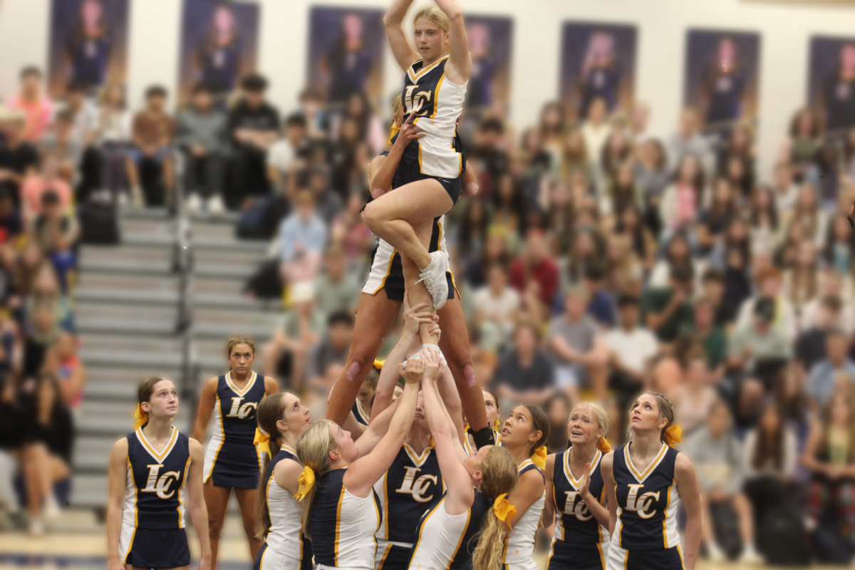 The cheerleading team holds freshmen Maylin Fay up at the pep rally opening show. Sophomore Sophia Cleary, junior Taylor Norton, freshmen Carson Vaughan, sophomore Caroline Ahearn watch from below. Photo by Dylan Keyes. 